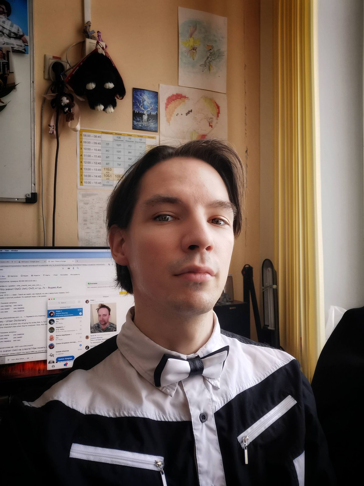 Юрий Самплин в кабинете информатики: белая бабочка, за спиной расписание и рисунки пони