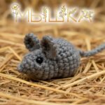 Вязаная мягкая игрушка-мышка, сделанная крючком, на фоне сена.